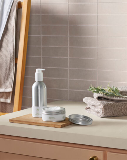 Body wash and body cream containers sit neatly on a bathroom sink countertop.