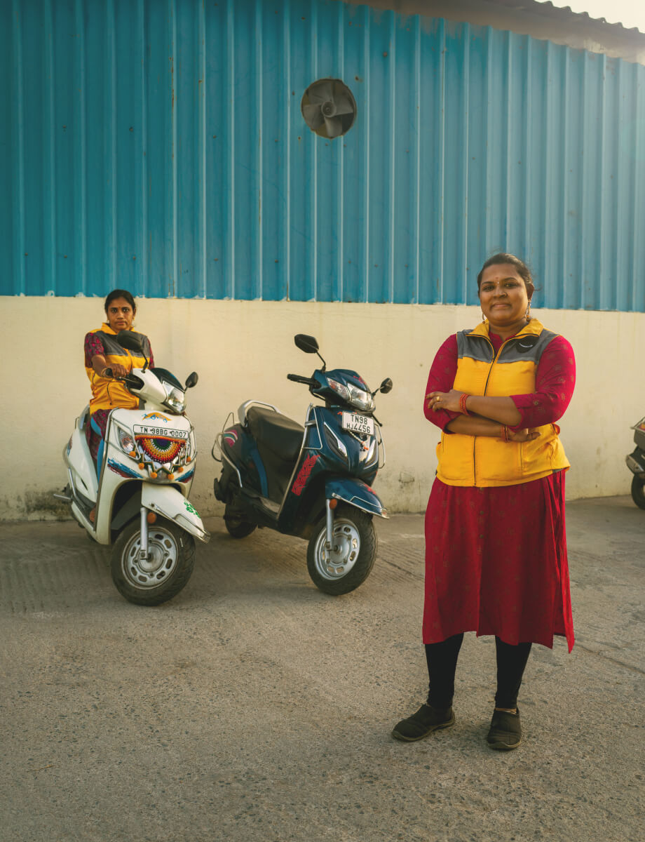 Two delivery drivers pose next to motor bikes.