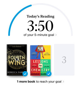 iPhone screen showing the Reading Goals interface in the Books app. At the top, there is a progress ring for a reading goal. Below the progress ring are three book covers. Beneath the book covers is text that one more book is needed to reach the 2024 goal of reading eight books.