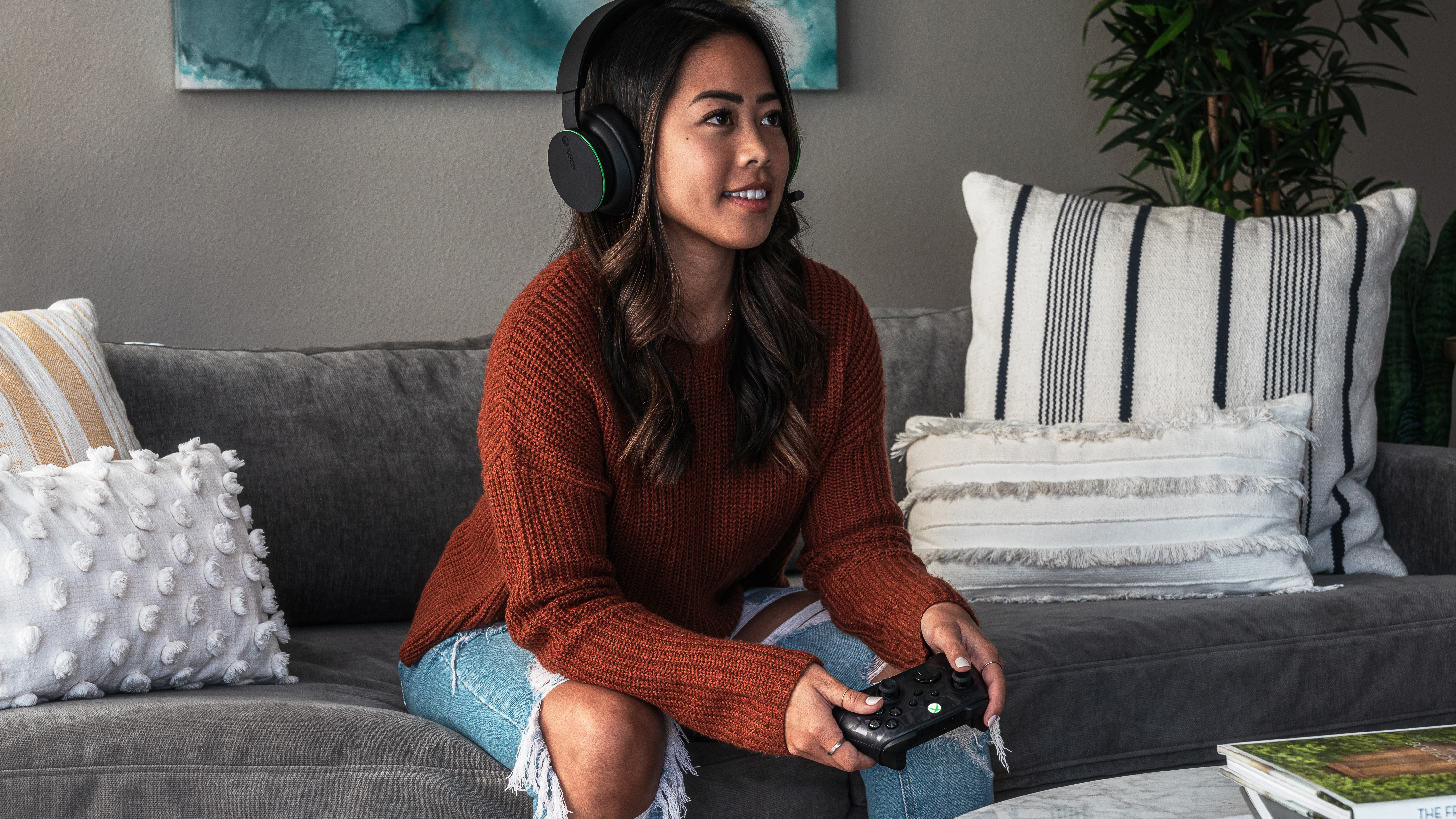 Person sitting on a couch with headphones and an Xbox controller