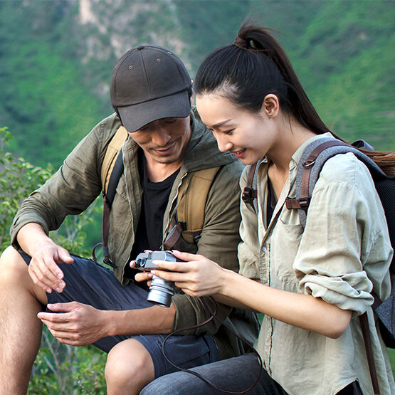 A couple look at photos together on a camera during a hike.