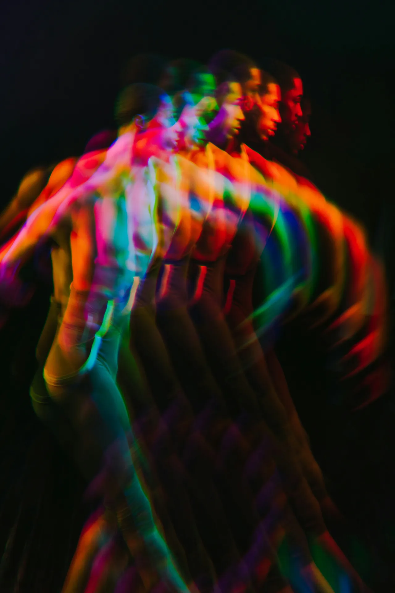 Colorful multi-exposure image of a person in motion against a dark background