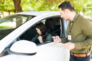 Women siting in driver seat of car while instructor watches