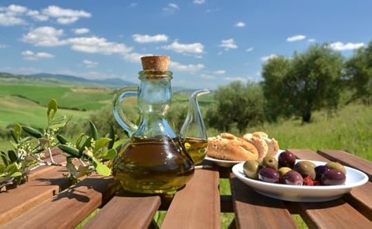 Olive-oil-olives-and-bread-on-the-wooden-table-against-Tuscan-landscape-Italy