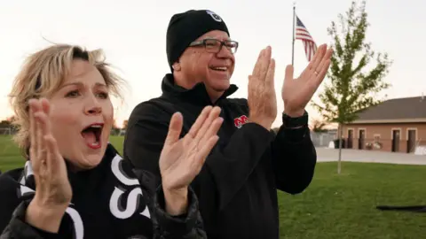 Gwen and Tim Walz clap