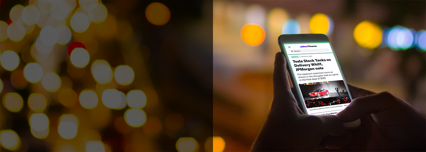 A person holding a mobile phone reading business news on Yahoo Finance