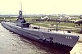 Photograph of the bow of the USS Drum, mounted on concrete supports on land as a museum ship.