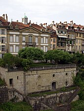 Photographie d'un bâtiment en pierre et d'un jardin attenant, sur le bord d'un vide.