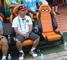 Vue d'un homme en basket, short et tee-shirt portant une casquette assis sur un fauteuil orange