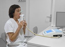 A person sitting and blowing into a device attached to a computer