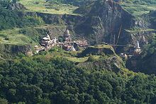 View of a mountainside with cliffs and domed structures built on the ledges.