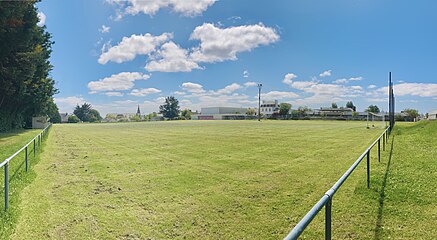 Le terrain de football de Corseul avec, en arrière-plan, l’église Saint-Pierre, la salle des sports, l’ArchéoMusée Coriosolis et l’école primaire publique.