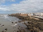 A seaside view of a large city enclosed by an orange barricade.