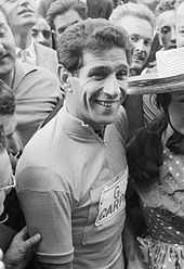 Photographie en noir et blanc d'un cycliste entouré par la foule.