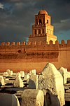 A picture with a dozen stone tombs, all of which are enclosed within a large wall. A large tower stands behind the wall several stories high.