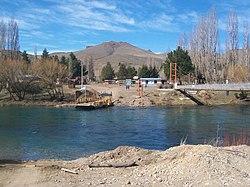 View of the hanging walkway over the Limay river and the raft for vehicle crossing in Villa Llanquín