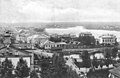 English: View from the top of the Holy Trinity Cathedral to Nikolskaya Street (nowadays Krasnaya). The second building over the bridge is a tavern (during the Soviet era Young Pioneers' House, later Municipal Council). In the background centre Finnish village Mokkala (nowadays Recreation Park). 1910's Русский: Вид с собора Святой Троицы на Никольскую улицу (ныне улица Красная). Второй дом за мостом — кабак (в советское время — Районный дом пионеров, затем Муниципальный совет города). Вдали в центре — финская деревня Мокколово (ныне Парк культуры и отдыха). 1910-е годы