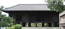 Bâtiment austère en poutres horizontales de bois nu.