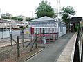 The station building had been unstaffed and boarded up for several years. It was boarded up shortly after being completely renovated, The station building was demolished in March 2015. Inverkip Road is to the left; Ravenscraig Court is obscured by the trees.