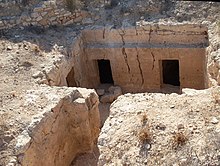 Vue plongeante sur une cavité dans le sol ouvrant sur des salles abritant des tombes puniques.