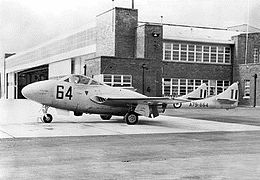 Photographie d'un avion militaire monomoteur stationné devant un bâtiment