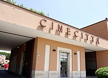 Bâtiment couleur orange avec deux porches et écrit en grosses lettres CINECITTA.