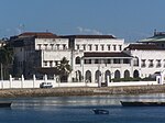 A distant view of a very large and luxurious building near a wide river.