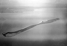 Photographie en noir et blanc et en altitude d'une étendue d'eau entourant une île