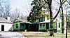 green wooden building, large driveway, trees