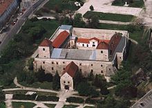 A castle with a large courtyard, a fortified entrance and two towers