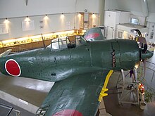 Photographie en couleur d'un monomoteur vert sombre se trouvant dans une salle.