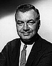 A black-and-white portrait photograph of a man wearing a suit