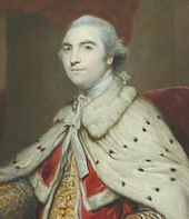 Half-length portrait of a man wearing furred robes and a white wig and looking regal. Underneath his white robes, he is wearing red and gold and he is sitting in a red chair.