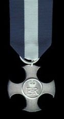 De medaille. Lint: 36mm, drie gelijke delen van donkerblauw, wit, en donkerblauw.