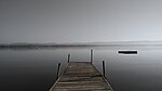 A dock extends from the shore of an extremely wide river.