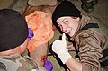 5 - Sabrina Harman stitches a wound on an Iraqi prisoner who has been bitten by a military dog.