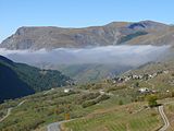 La route du col du Lautaret et le hameau des Cours ; en fond d'image, le plateau d'Emparis.