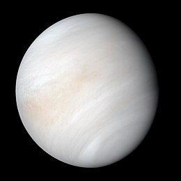 Venus in approximately true colour, a nearly uniform pale cream, although the image has been processed to bring out details.[၁] The planet's disc is about three-quarters illuminated. Almost no variation or detail can be seen in the clouds.