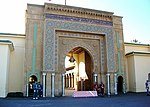 A large, architecturally detailed entrance to a big palace. Several guards are posted out front.