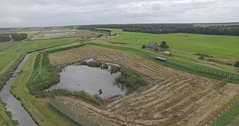 Photographie en couleurs et prise en hauteur d'un plan d'eau entouré par un paysage rural