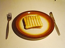 Photographie d'une assiette avec du pain de mie marqué de traits verticaux plus sombres.