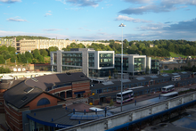 Sheffield Interchange, the main hub for bus and coach operations in Sheffield. In the foreground is the interchange itself. Visible in the bottom left corner is the new, main entrance to the interchange. In the centre are the long bus stands that form the interchange. Above that is the Digital Campus commercial development built upon an unused section of the interchange. In the top left corner is the 1960s Park Hill flats development and to the right is Sheffield Railway Station.