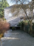 Vue d'un bâtiment établi au-dessus d'un cours d'eau. Vestiges d'une roue à aubes visible sous le bâtiment.