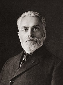 A photograph of a man in late middle age, with a short, neatly-trimmed beard, wearing formal dress.