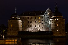 Château médiéval de nuit, éclairé par de faibles lumières.