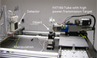 Eine Sub-Mikro-CT-Anlage. Rechts die Röhre, links der Detektor. Sehr nah an der Röhre und sehr klein das Prüfobjekt auf einer Nadelspitze auf einem Drehteller.