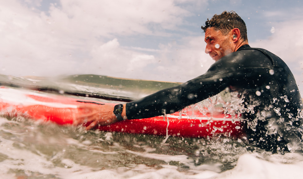 Una persona que hace surf en un mar agitado y lleva un Apple Watch Series 10.