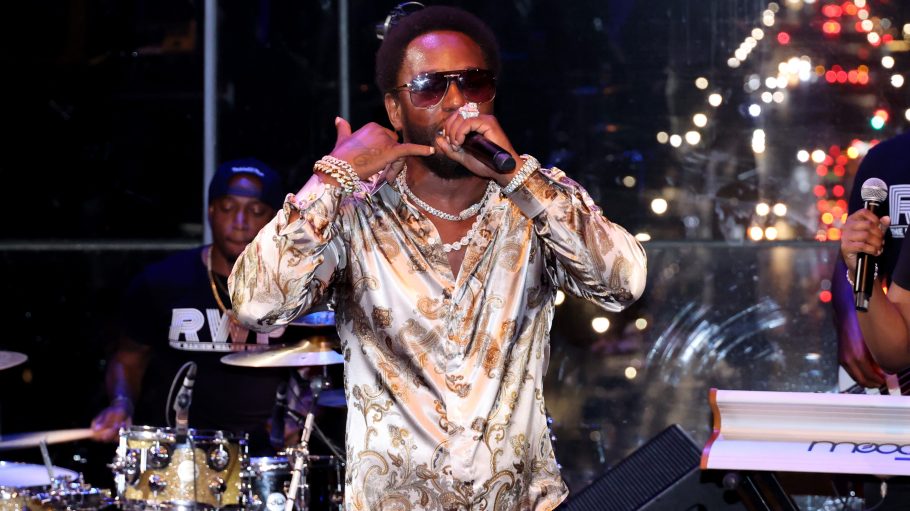 Cam'ron performing at Harlem's Fashion Row 15th Anniversary Fashion Show, wearing a multi-colored silk shirt and shades.